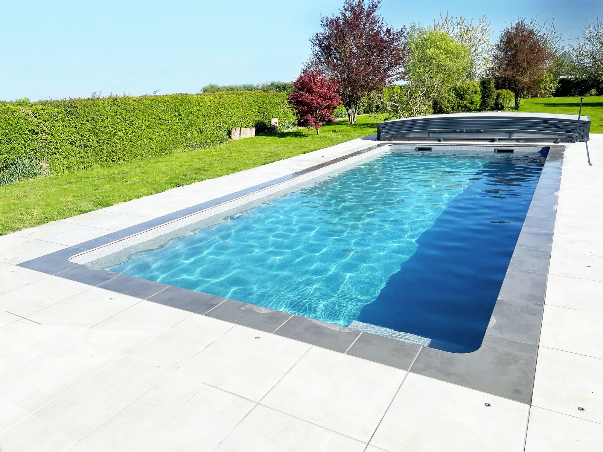 Réalisation d'une piscine avec une membrane armée grise et abri télescopique dans le Nord Piscine avec une membrane armée grise et abri télescopique dans le Nord