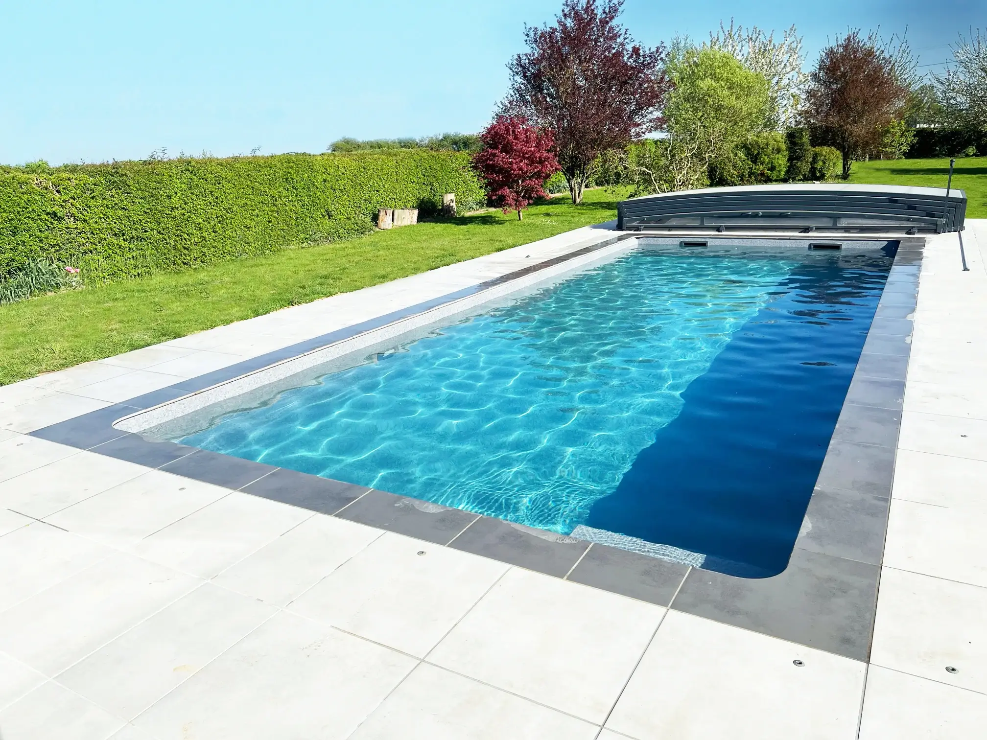 Piscine avec une membrane armée grise et abri télescopique dans le Nord